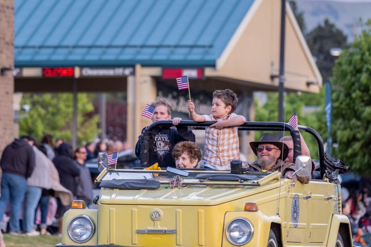 Yellow Willys convertible with a young boy holding an American flag.
