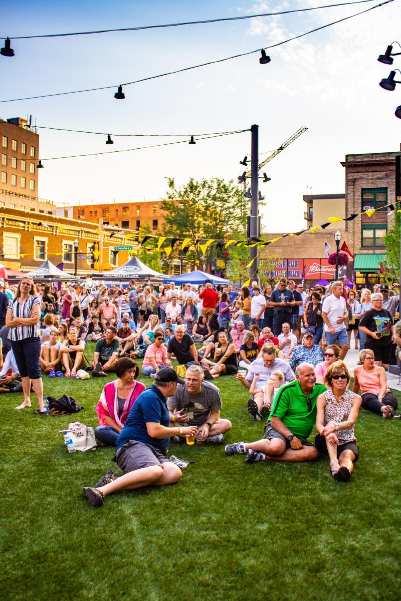 Spectators rest on table, chairs and turf at Fargo Broadway Square during the Street Fair.