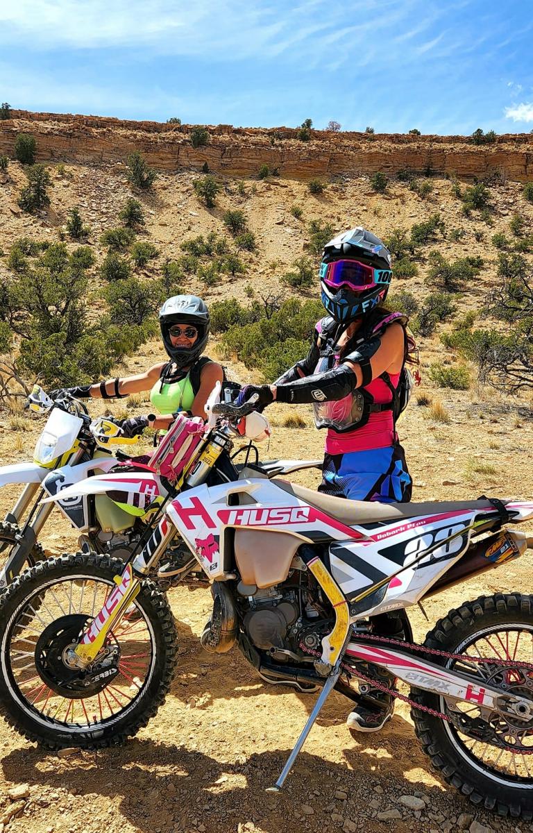 two women with their dirt bikes on trail