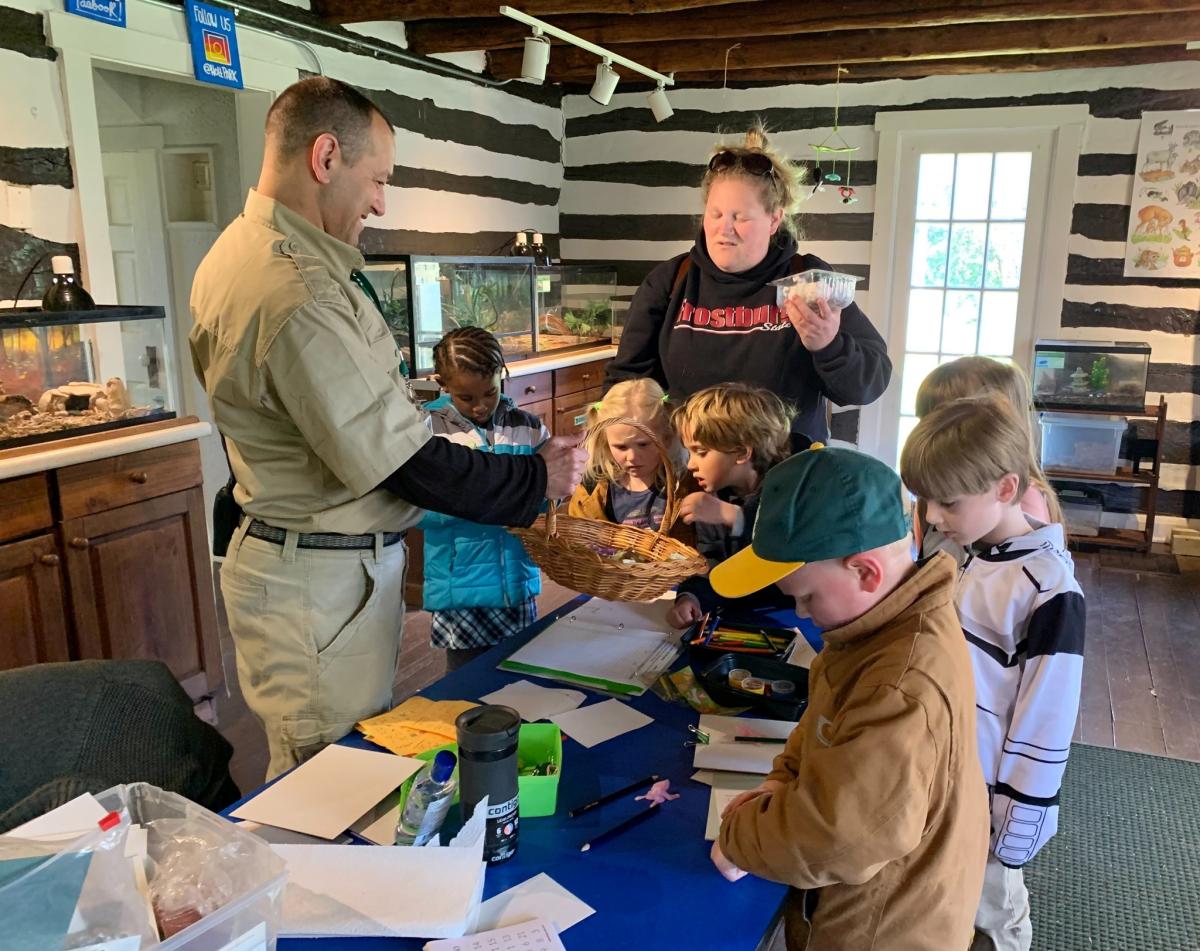 Naturalist surrounded by children working on an animal project